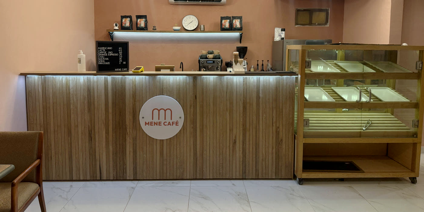 Barra de Mene Café con la máquina de espresso y el pizarrón del menú